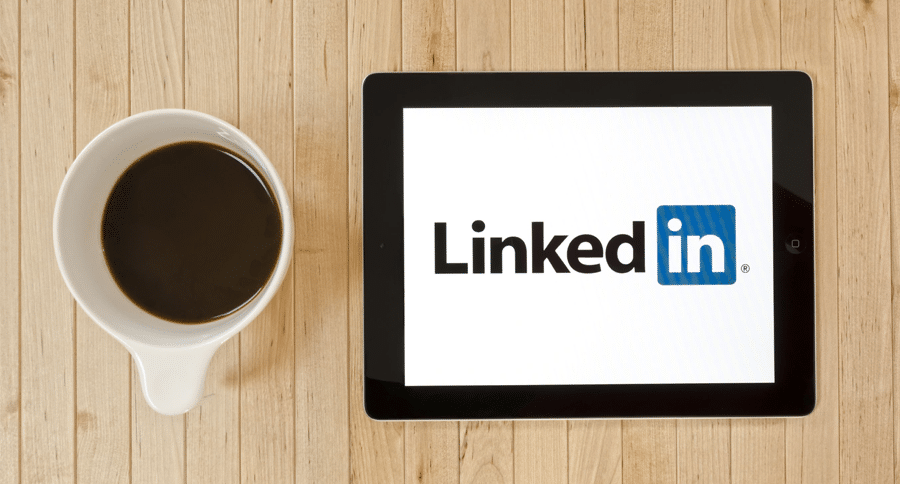 LinkedIn logo on a tablet with a coffee up next to it.