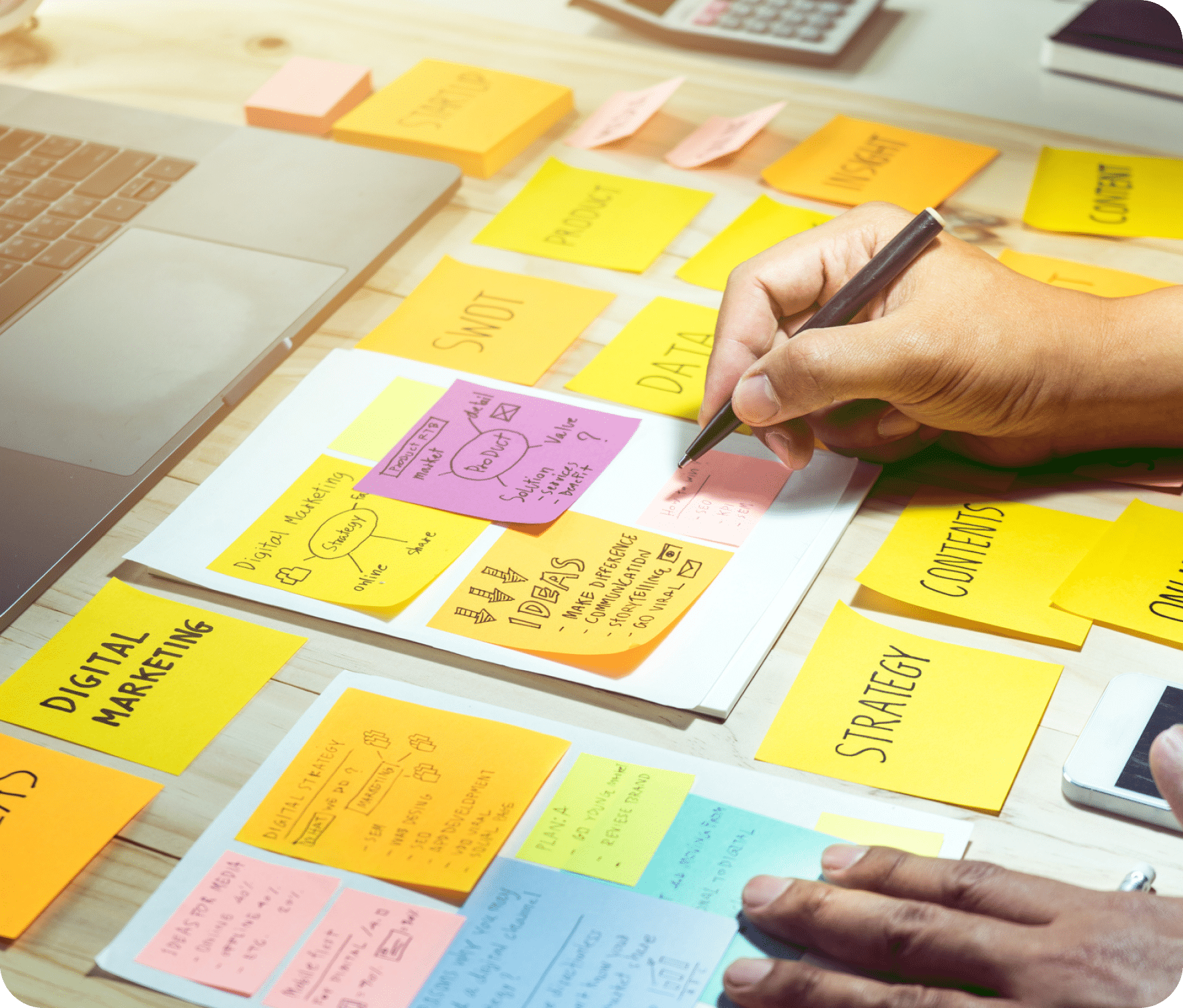 Person planning content strategy with various sticky notes of different colors on a desk.