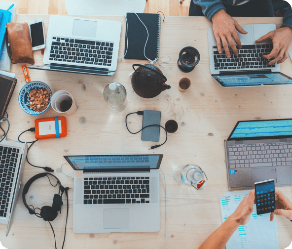 Integrated services strategy building with four laptops, mobile phones and cups around a table.