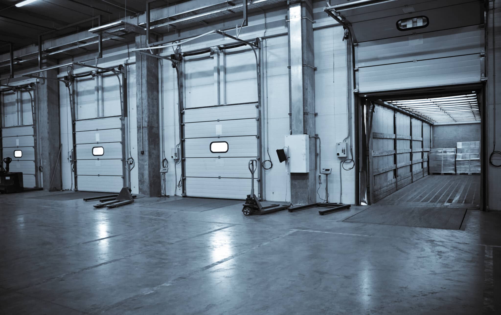 Overhead doors in various states of open and closed at a loading and unloading dock for truck trailers.