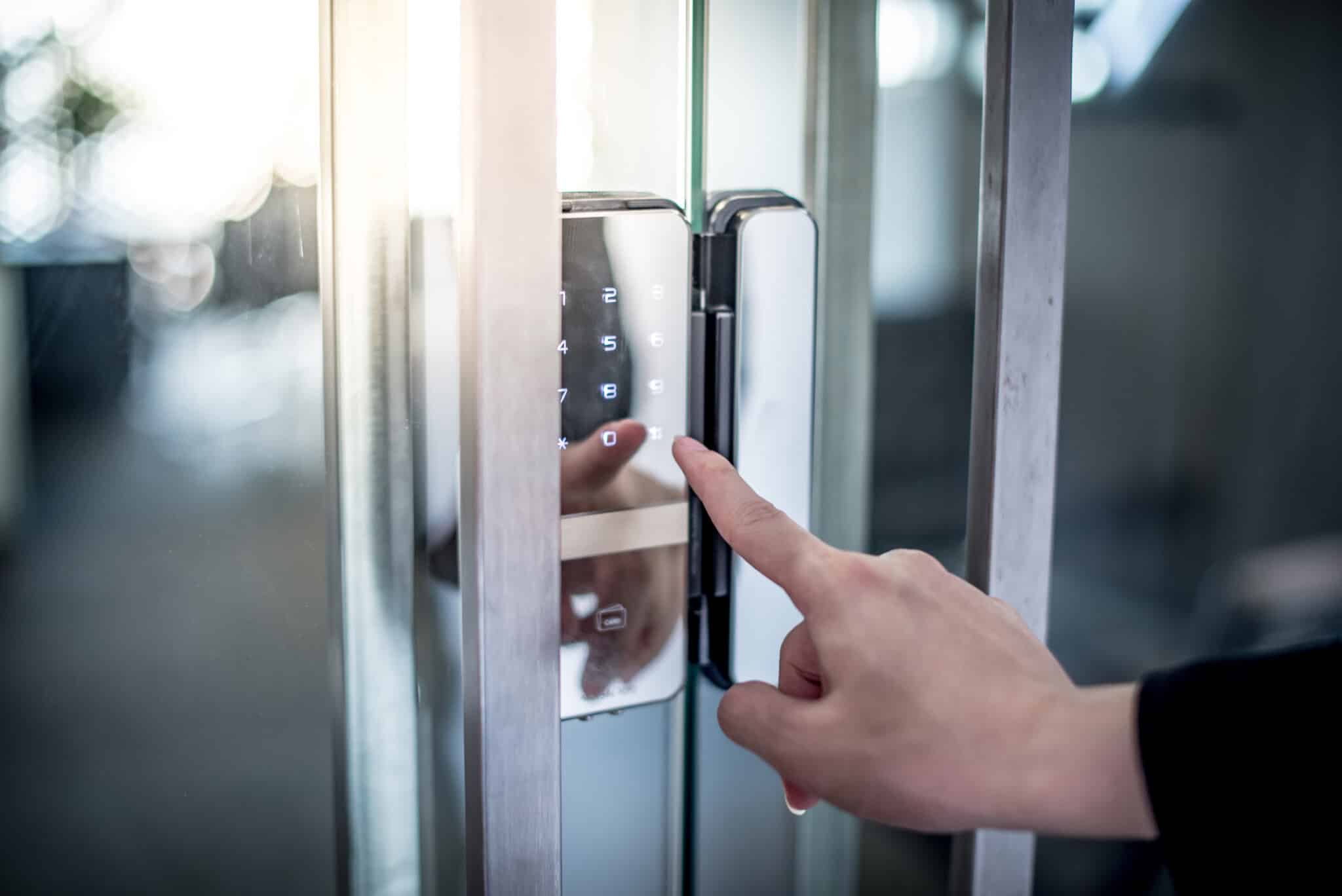 Persons pointer finger enters in their code on an access control door keypad to gain entry to a building.