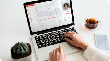 Person sits at desk with laptop open to Landmark reporting showing line chart data insights.