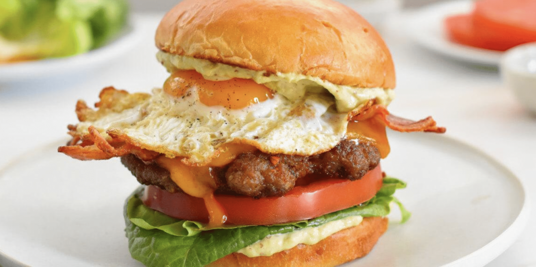 Swaggerty's Sausage breakfast sandwich with bun, egg, bacon, cheese, sausage patty, tomato, and lettuce.