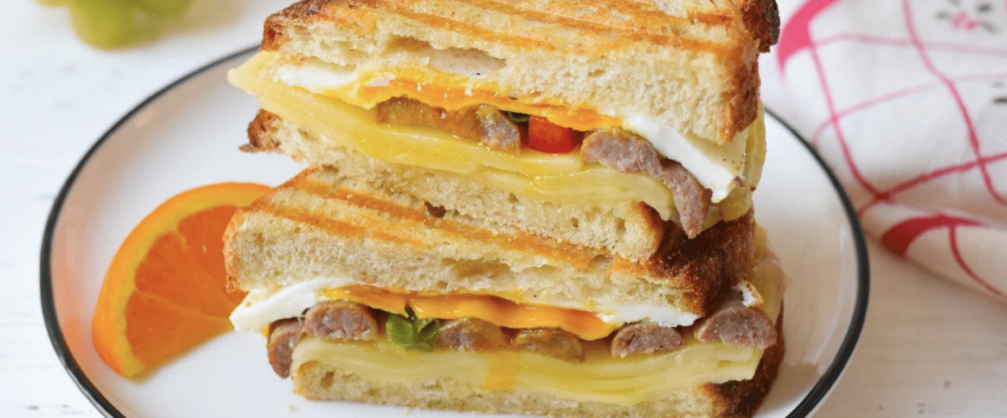 Swaggerty's Sausage links on a grilled cheese sandwich, plated with an orange slice.