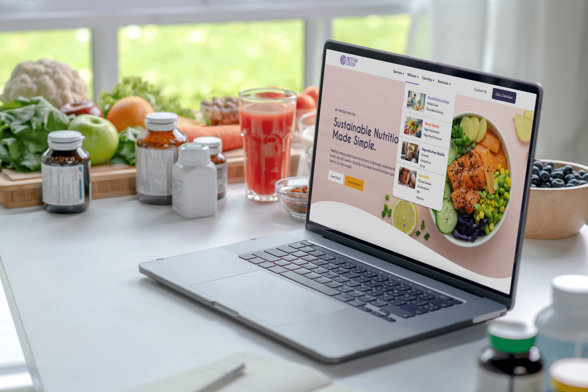 An open laptop sits on a table with the Dietitian Group website showing the homepage.
