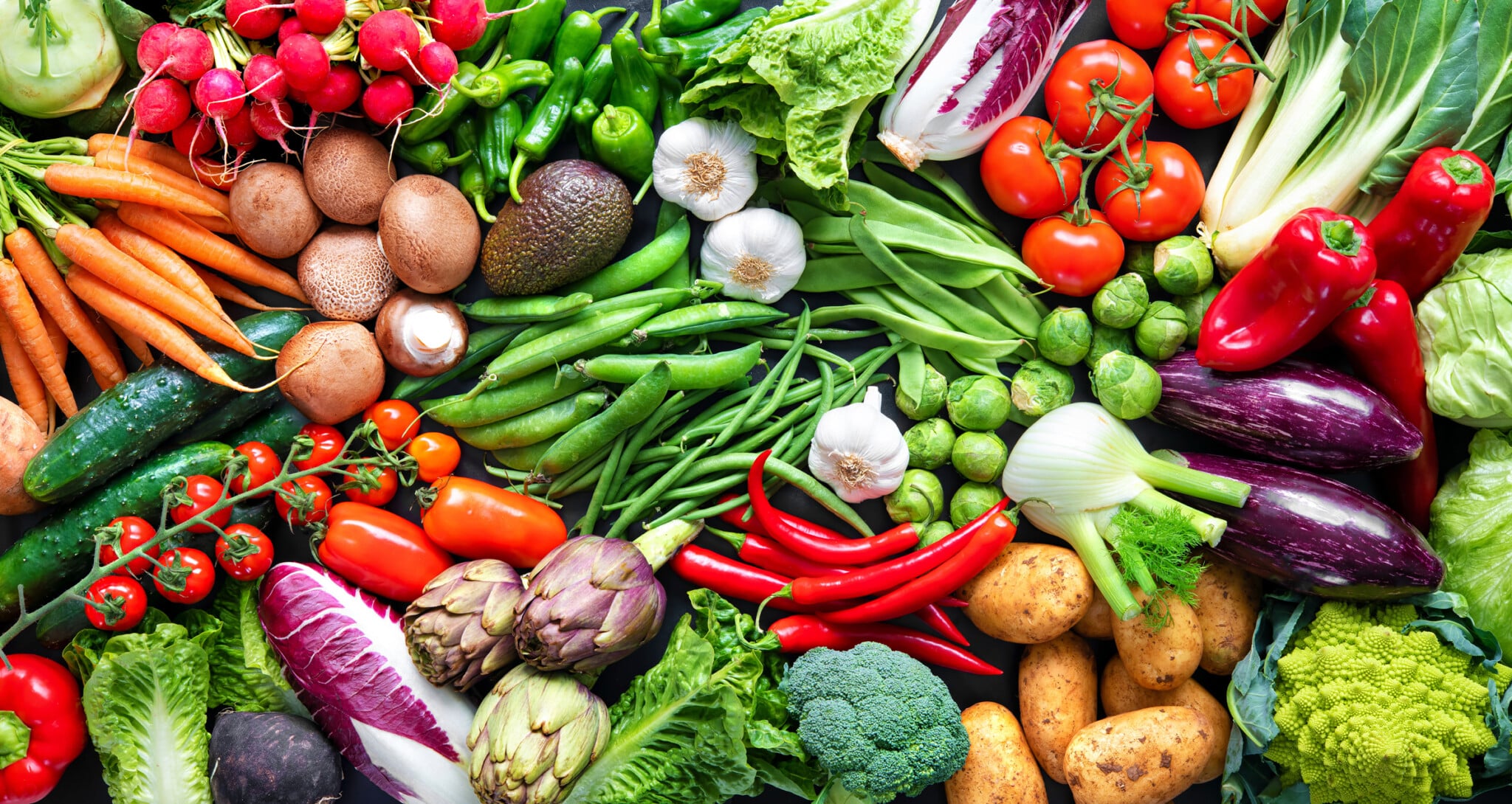Different types of colorful organic vegetables laid out in a panoramic view.