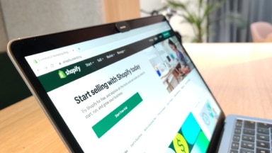 Open laptop shows Shopify webpage.