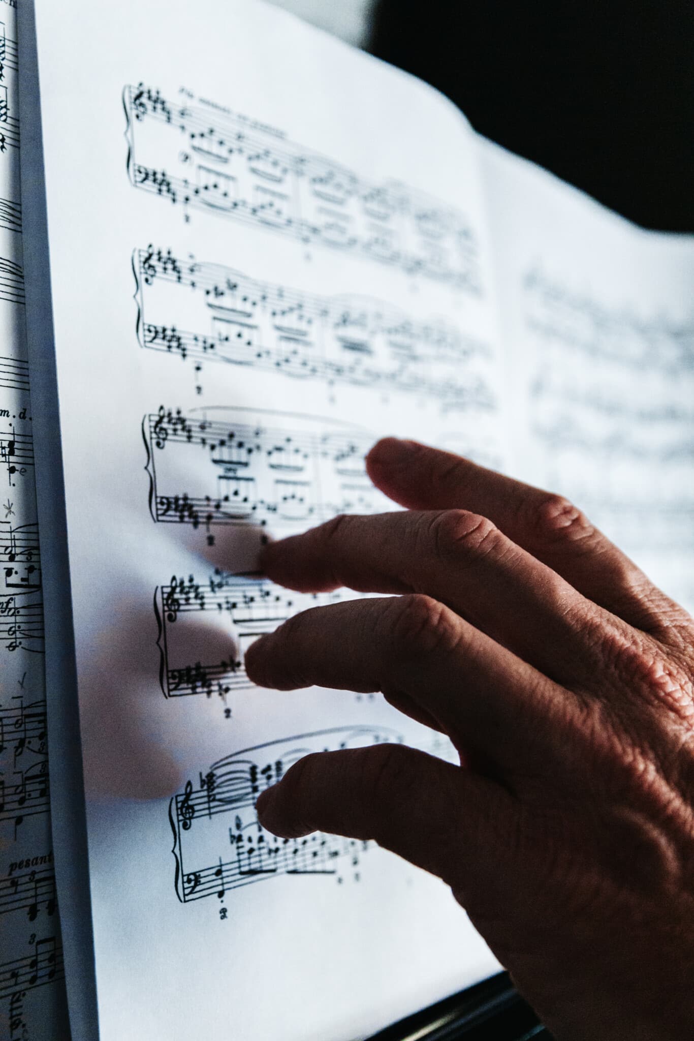 A persons hand touches the pages of sheet music.