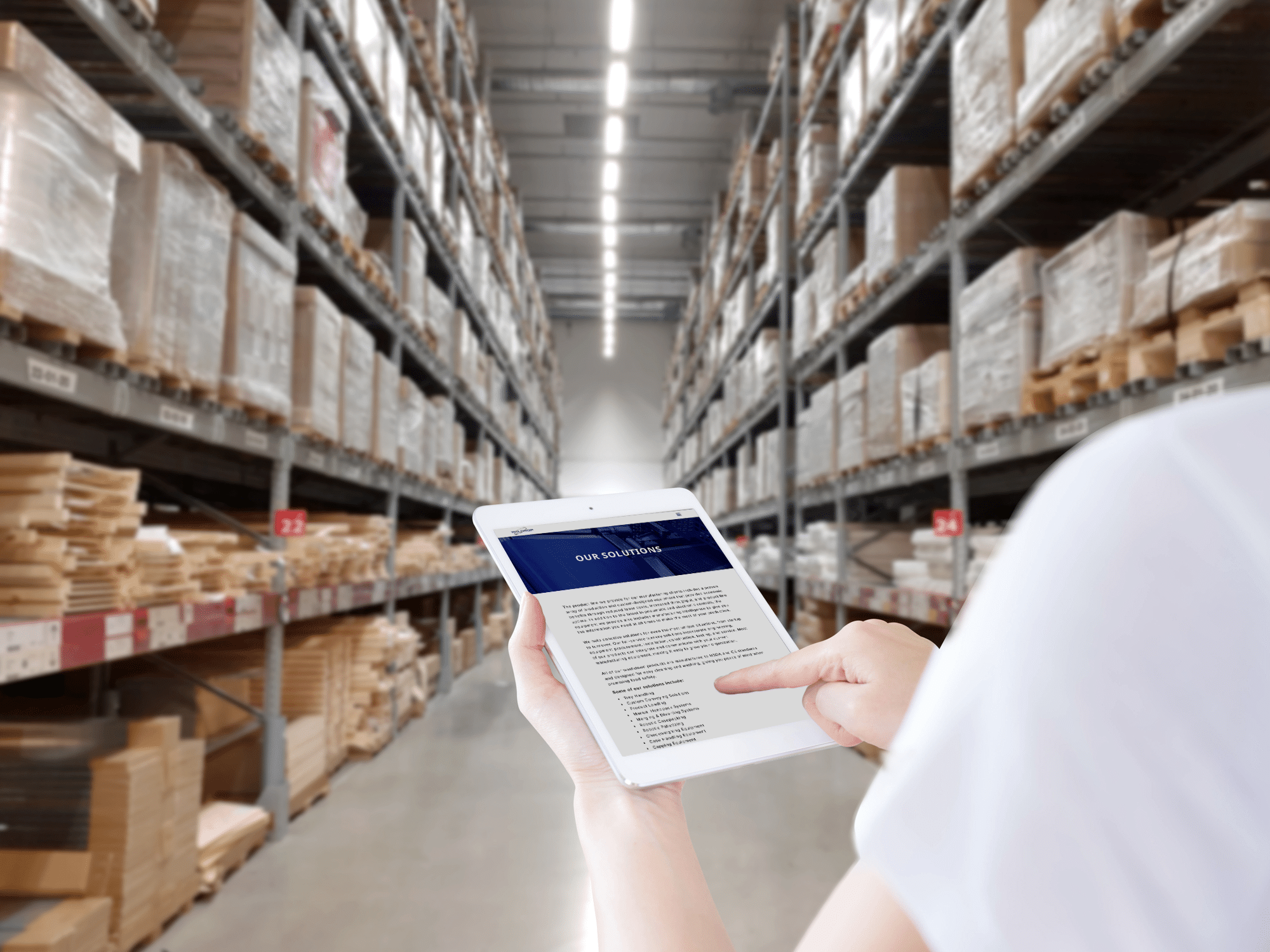 Person holds a tablet standing in the aisle of a warehouse looking a the Waldrop Solutions webpage.