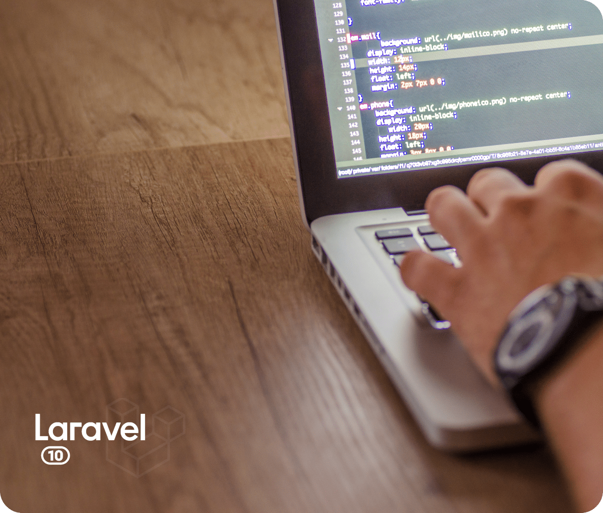 A Laravel developer sits at an open laptop with code on the screen for a website being worked on.