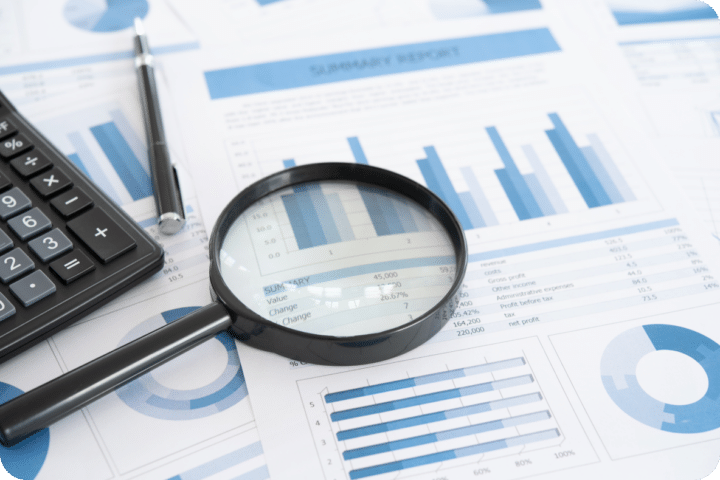 A magnifying glass is placed over a couple of papers with data in charts and graphs showing Ads information for strategy.